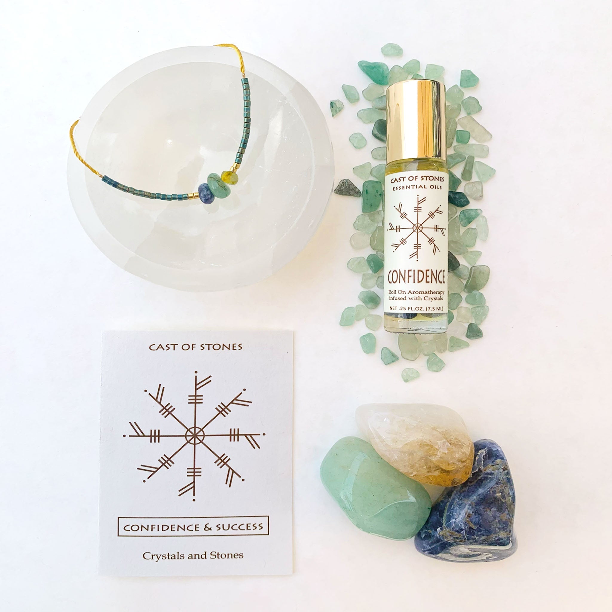 Roll-on bottle labeled 'Confidence', necklace, stones, and card on a white background